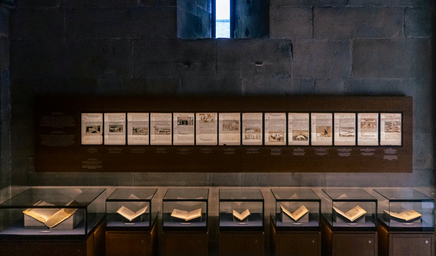 Historical artifacts and open books displayed in museum exhibit cases.