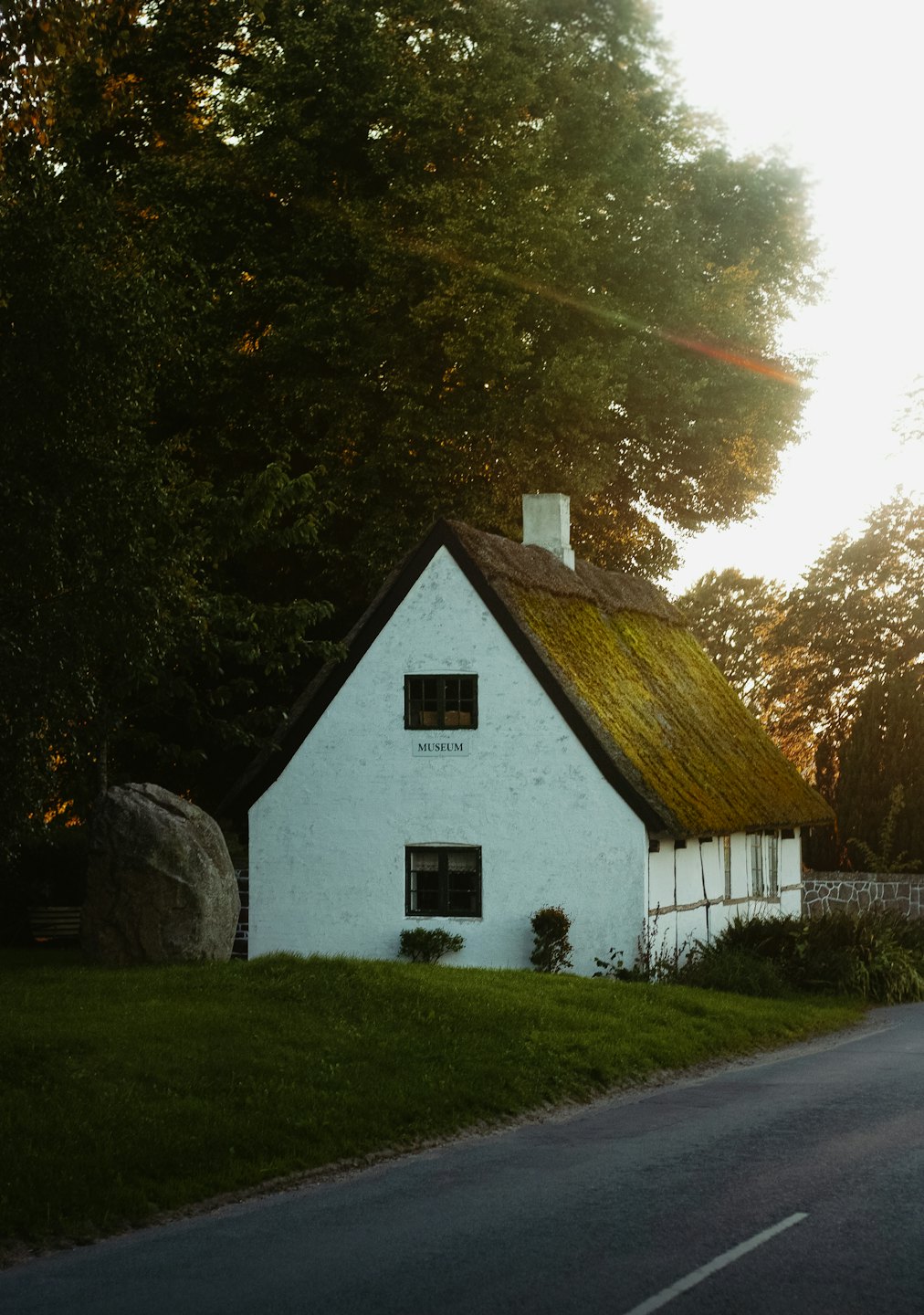 A rustic white museum building with a mossy thatched roof.