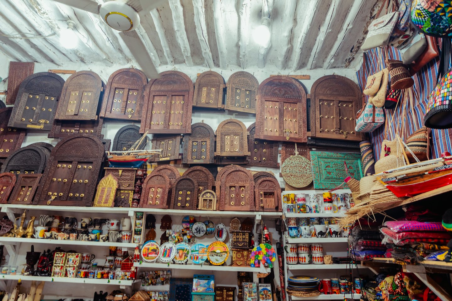 Souvenir shop shelves filled with ceramics, carvings, and textiles.