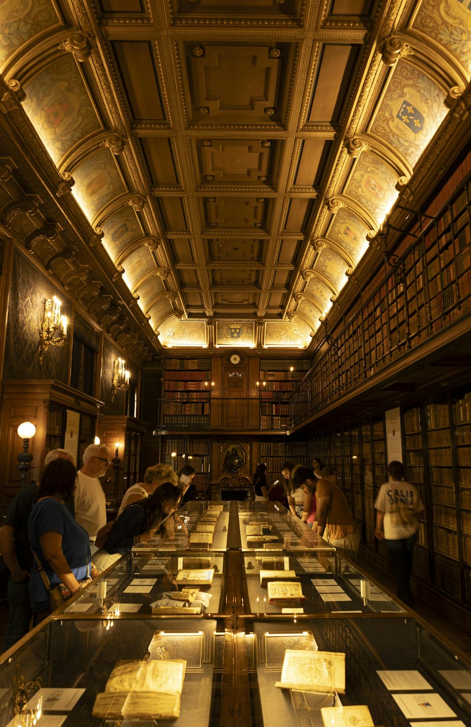 Visitors examine historical documents displayed inside an ornate library archive.