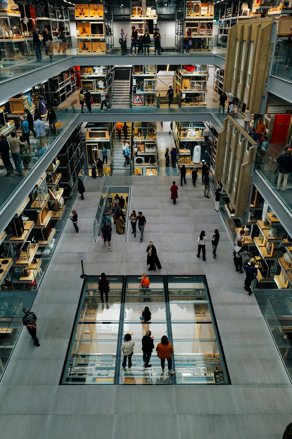 Visitors explore a modern museum with metal shelving and glass walkways.